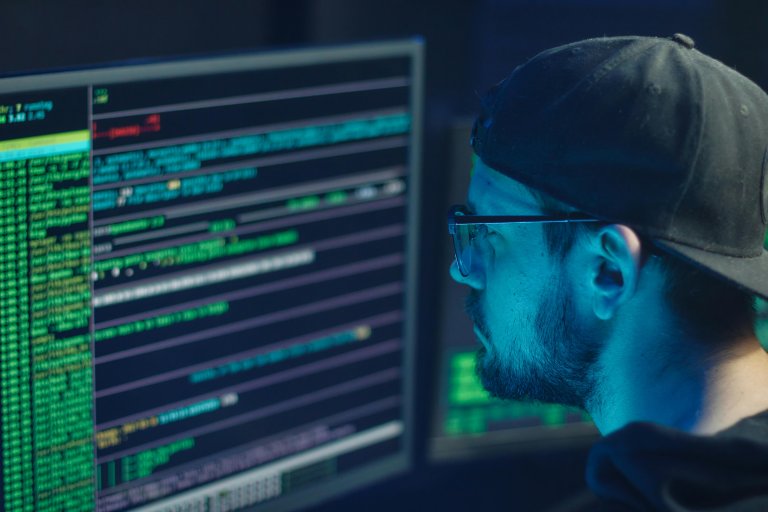 Profesional revisando código y alertas de seguridad en un monitor, ilustrando la suplantación de identidad