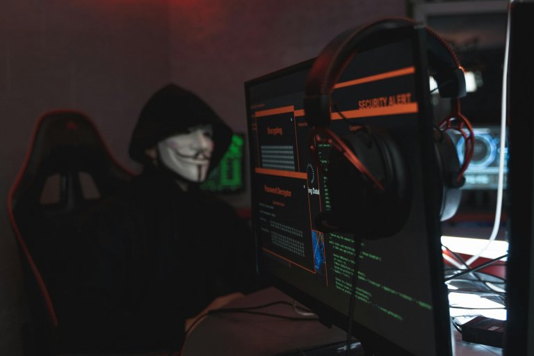 Persona con máscara frente a un computador, representando a un atacante de phishing